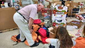 County Comissioner Larry Hudkins helps sort backpacks with AmeriCorps volunteers for Tools For Education, July 27 at the Center for People in Need